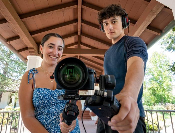 Students holding a camera and a mic toward the camera